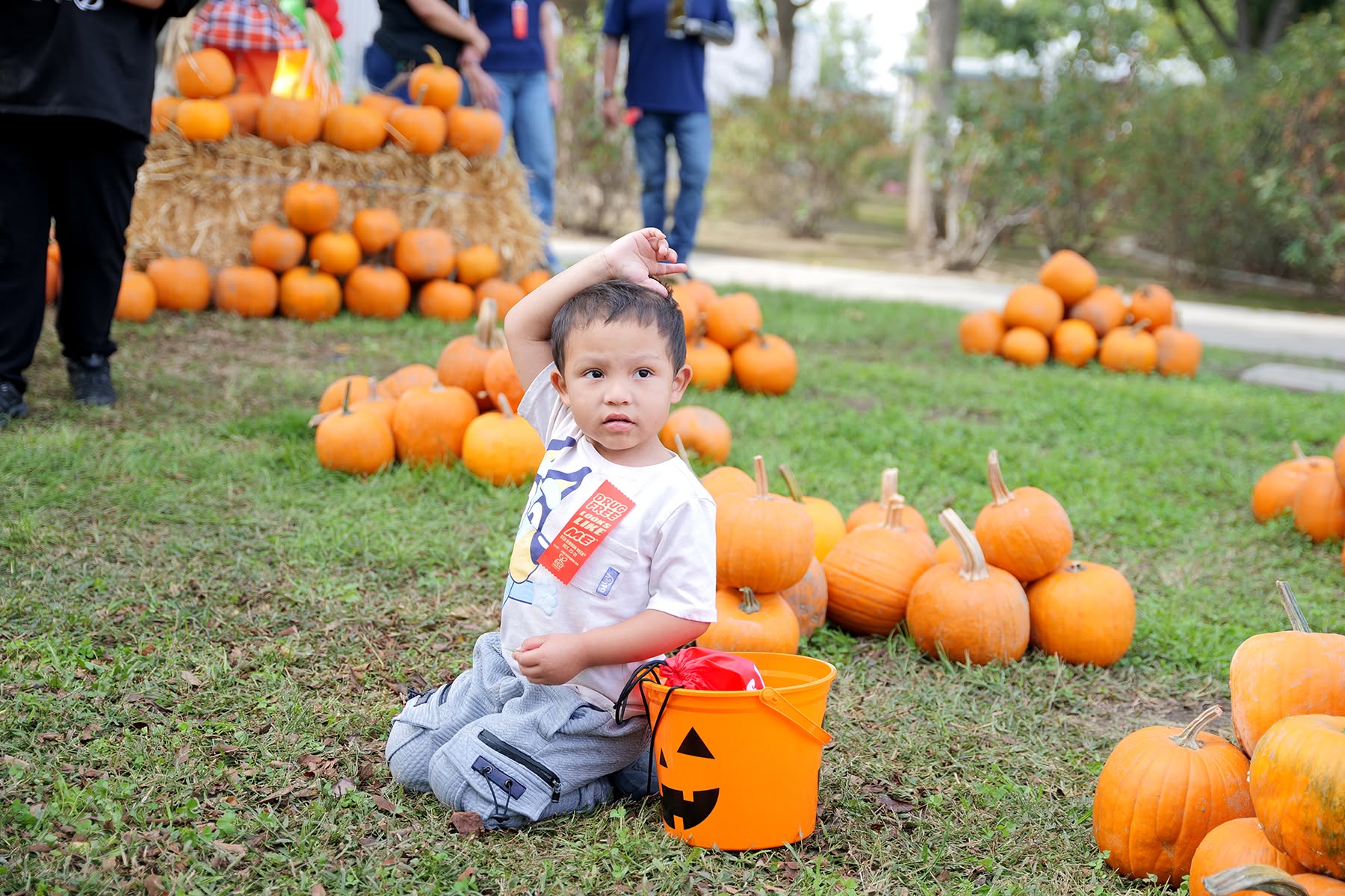 Student sitting in pumpkin patch with a bucket of candy.