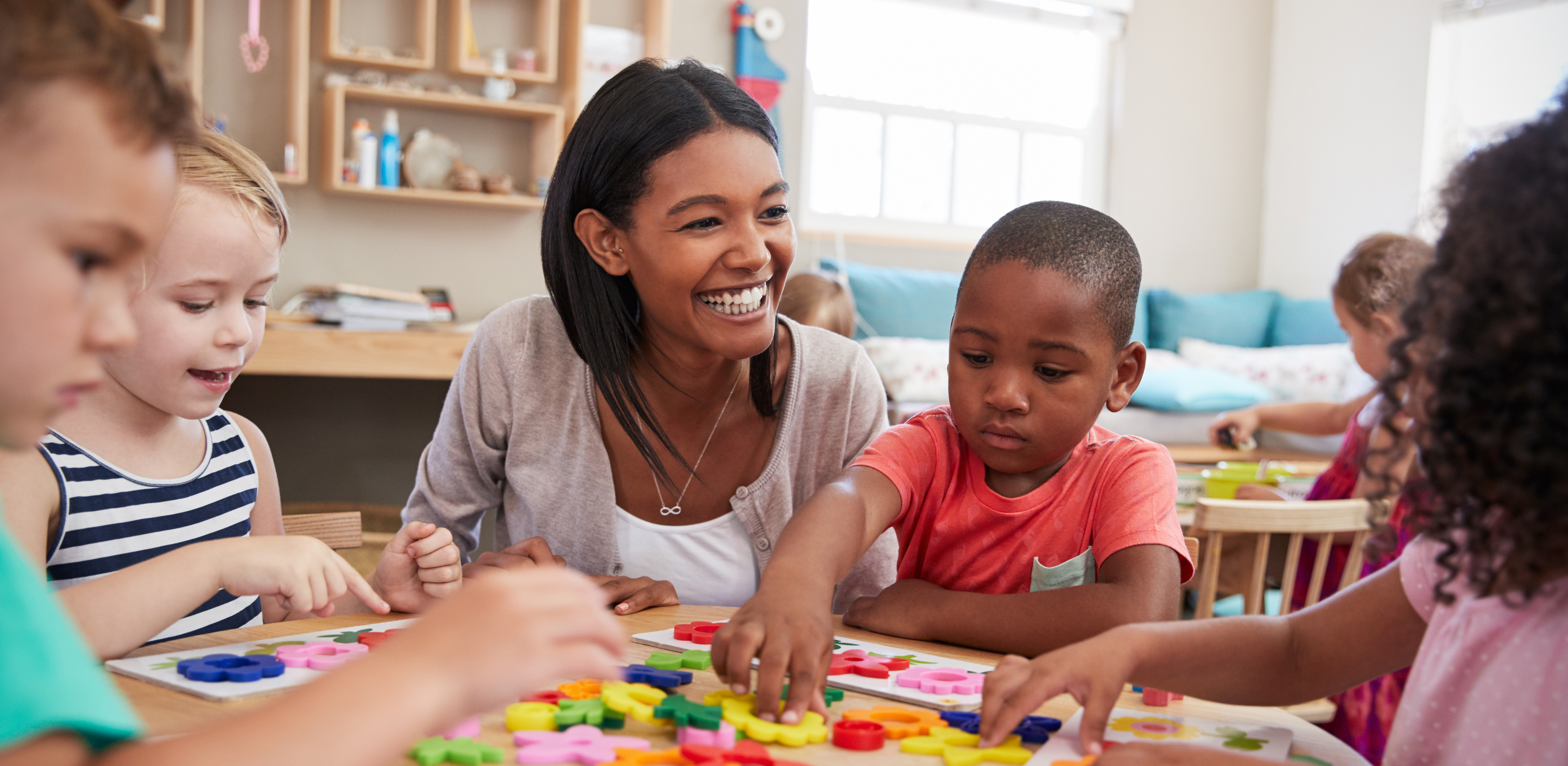 AdobeStock_154985520 Teacher with children at table